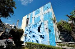 A giant lion roars before a frayed Greek flag on a graffiti by BANE on a wall of a primary school in the Athens suburb of Nikaia on this picture taken at the end of April.Jun 15, 2014, afp